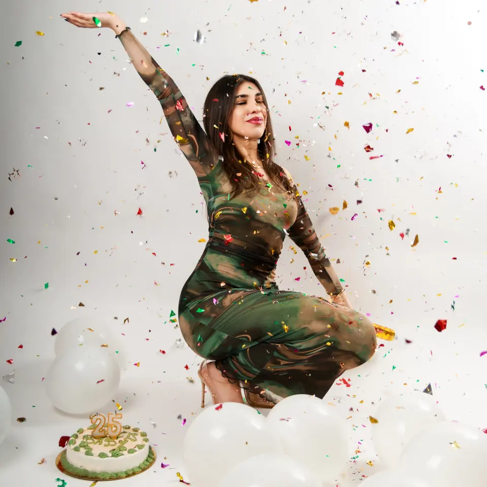 Femme en robe verte dansant sous les confettis en studio