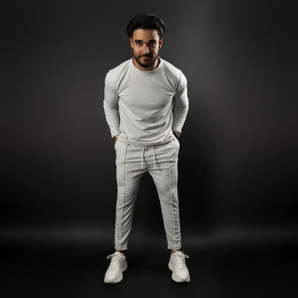 Homme en ensemble blanc posant sur fond noir
