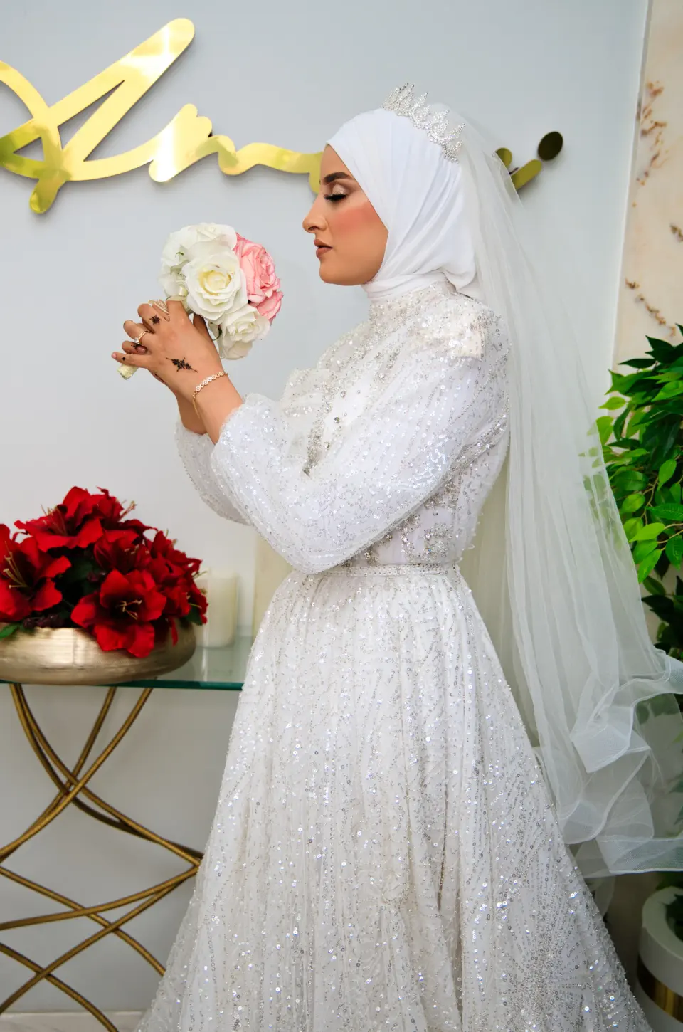 Mariée voilée respirant son bouquet de roses blanches